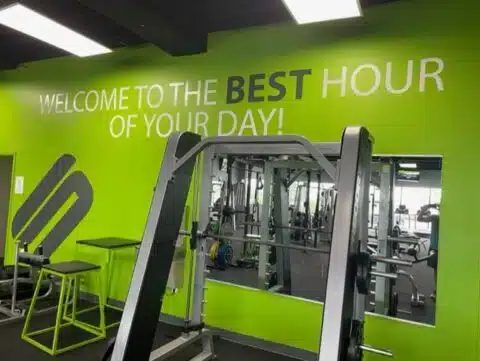 Strength equipment in front of the Best Hour of Your Day wall at Shape Plus DTC